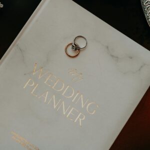 Close-up of a wedding planner book adorned with silver rings, symbolizing preparation and commitment.