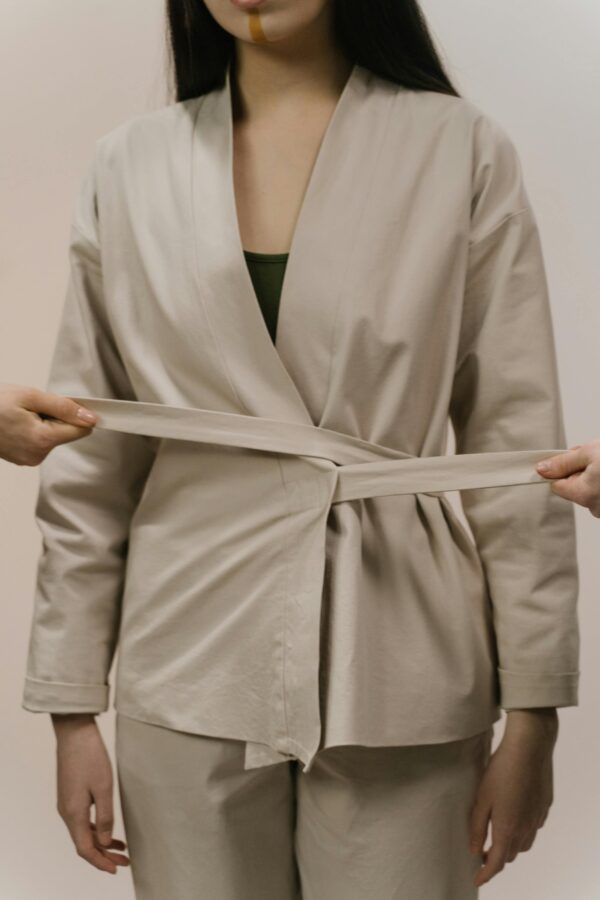 A symbolic image of a woman in beige attire with hands adjusting a sash, reflecting boundary concepts.