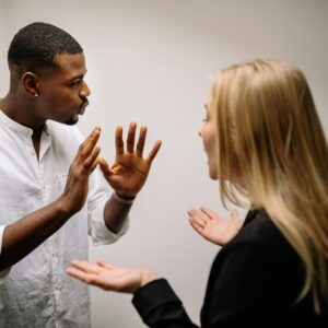 Frustrated coworkers in heated discussion, expressing disagreement in office setting.
