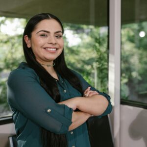 Portrait of a confident businesswoman standing with arms crossed in modern office space.
