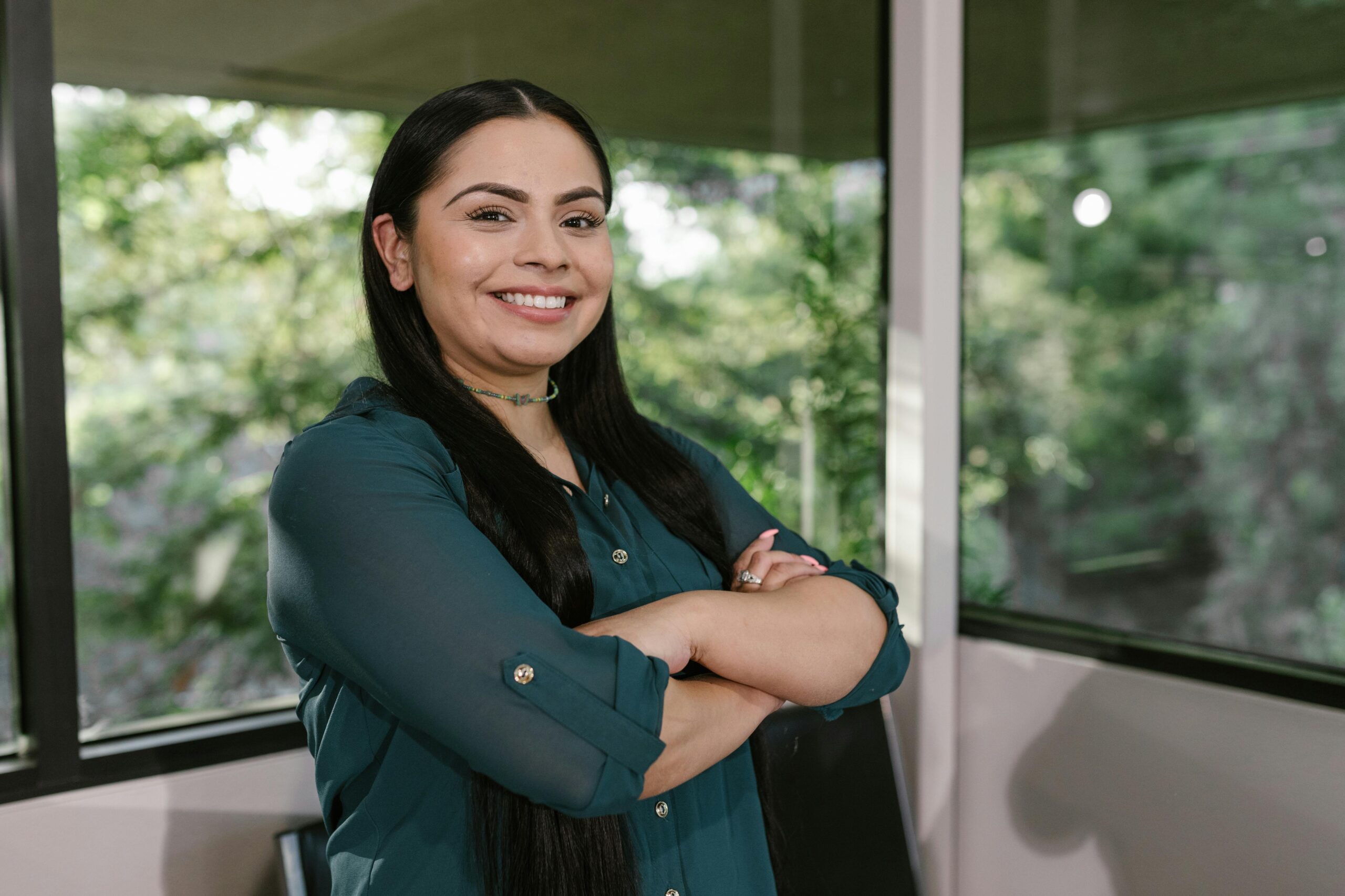 Portrait of a confident businesswoman standing with arms crossed in modern office space.