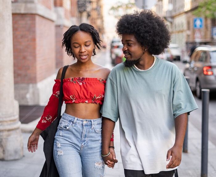 A young couple holding hands and walking on urban streets in Budapest, Hungary.