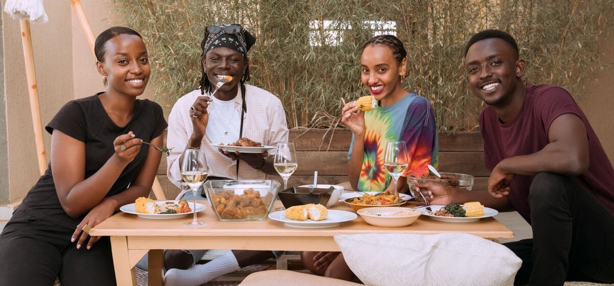 Four friends smiling and enjoying a meal together, exuding joy and togetherness.