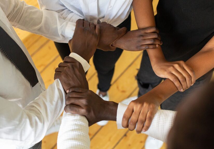 Close-up of diverse hands in a circle, symbolizing teamwork and unity.